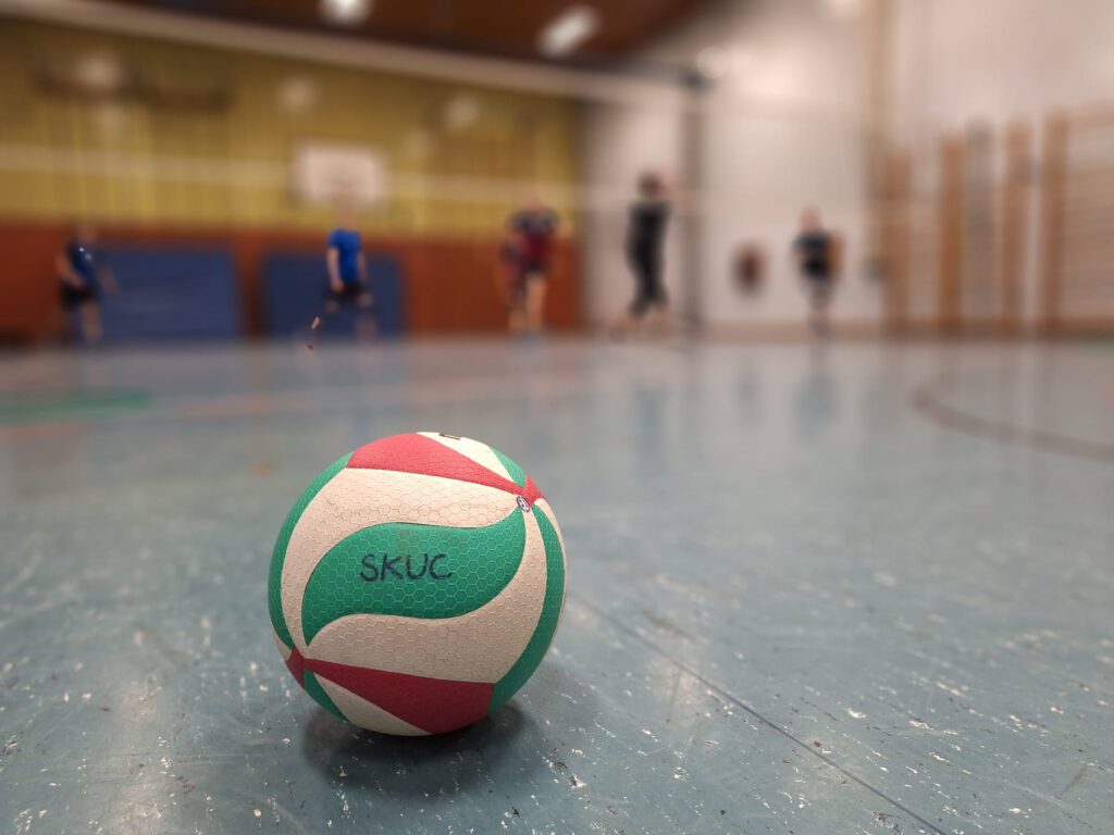Volleyball mit Aufschrift SKUC liegt in der Sporthalle.